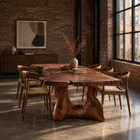 Live edge dining table with a thick top and a sculpted arched base in an industrial loft dining room with exposed brick