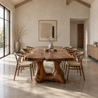 Live edge dining table with a thick top and a sculpted arched base in a bright open plan dining room