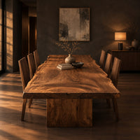 Live edge dining table with a swirling grain top on one block base in a dark dining room at golden hour