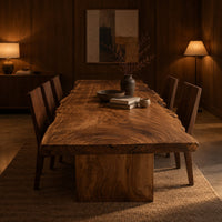 Live edge dining table with a swirling grain top on one block base in an evening dining room with walnut wall paneling