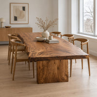 Live edge dining table with a swirling grain top on one block base in a Scandinavian dining room with white walls