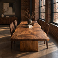 Live edge dining table with a swirling grain top on one block base in an industrial loft dining room with exposed brick