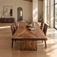 Live edge dining table with a swirling grain top on one block base in a bright open plan dining room