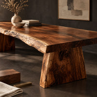 Corner detail of live edge dining table with a thick slab top and tapered block base beside wood, brass and linen samples