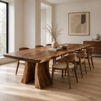 Dining table with a thick live edge slab top on two flared pedestal legs in a Scandinavian dining room with white walls