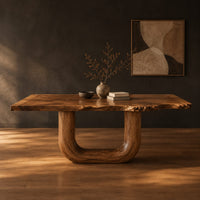 Live edge dining table on two thick u shaped legs in a dark studio against a charcoal plaster wall