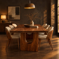 Long dining table with a live edge top and two arched pedestal legs in a dark dining room at golden hour