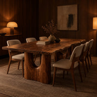 Long dining table with a live edge top and two arched pedestal legs in an evening dining room with walnut wall paneling