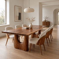 Long dining table with a live edge top and two arched pedestal legs in a Scandinavian dining room with white walls
