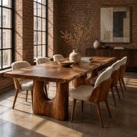 Long dining table with a live edge top and two arched pedestal legs in an industrial loft dining room with exposed brick