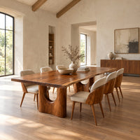 Long dining table with a live edge top and two arched pedestal legs in a bright open plan dining room