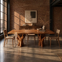 Live edge dining table on two branching tree trunk pedestals in an industrial loft dining room with exposed brick