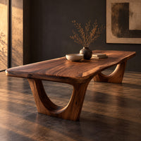 Corner detail of live edge wooden dining table on two arched pedestal legs beside wood, brass and linen samples