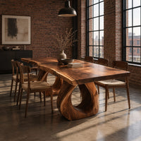 Rectangular dining table with a live edge slab top and two loop pedestals in an industrial loft dining room with exposed brick