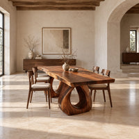 Rectangular dining table with a live edge slab top and two loop pedestals in a bright open plan dining room