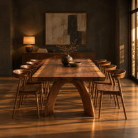 Live edge dining table with a thick slab top and two arched legs in a dark dining room at golden hour