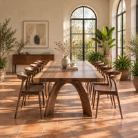 Live edge dining table with a thick slab top and two arched legs in a bright dining room with arched windows and plants