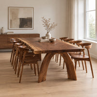 Live edge dining table with a thick slab top and two arched legs in a Scandinavian dining room with white walls