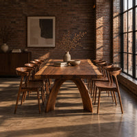 Live edge dining table with a thick slab top and two arched legs in an industrial loft dining room with exposed brick