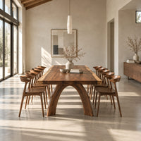Live edge dining table with a thick slab top and two arched legs in a bright open plan dining room