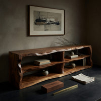 Corner detail of live edge TV cabinet with open shelves beside wood, brass and linen samples