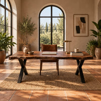 Live edge desk with a natural slab top and black crossed legs in a bright home office with arched windows and plants