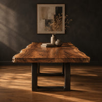 Live edge slab dining table on two dark squared frame legs in a dark studio against a charcoal plaster wall