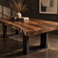 Corner detail of live edge slab dining table on two dark squared frame legs beside wood, brass and linen samples