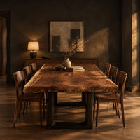 Live edge slab dining table on two dark squared frame legs in a dark dining room at golden hour