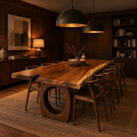 Long live edge slab dining table on thick ring shaped bases in an evening dining room with walnut wall paneling