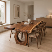 Long live edge slab dining table on thick ring shaped bases in a Scandinavian dining room with white walls