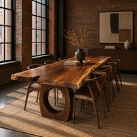 Long live edge slab dining table on thick ring shaped bases in an industrial loft dining room with exposed brick