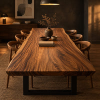 Thick wooden slab table top with a wavy natural edge and swirling grain in a dark dining room at golden hour