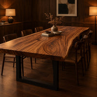 Thick wooden slab table top with a wavy natural edge and swirling grain in an evening dining room with walnut wall paneling