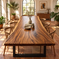 Thick wooden slab table top with a wavy natural edge and swirling grain in a bright dining room with arched windows and plants