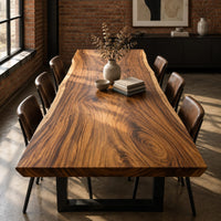 Thick wooden slab table top with a wavy natural edge and swirling grain in an industrial loft dining room with exposed brick