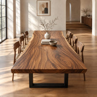 Thick wooden slab table top with a wavy natural edge and swirling grain in a bright open plan dining room