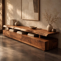 Corner detail of long low tv stand with a natural edge slab top over a block base beside wood, brass and linen samples