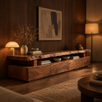 Live edge tv stand with a raised slab top and an open display gap in an evening living room with walnut wall paneling