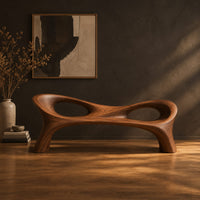 Long wood bench with a pinched middle and two oval openings in a dark studio against a charcoal plaster wall