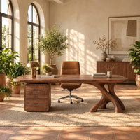 Desk with a long soft cornered top, three drawer block and branch leg in a bright home office with arched windows and plants