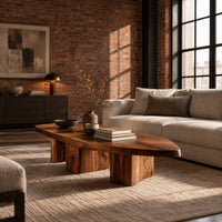 Leaf shaped coffee table with a pointed slab top on three chunky block legs in an industrial loft living room with exposed brick