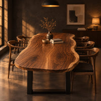 Long freeform wood table top with rippling live edge sides and warm grain in a dark dining room at golden hour