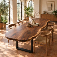 Long freeform wood table top with rippling live edge sides and warm grain in a bright dining room with arched windows and plants