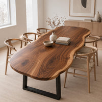 Long freeform wood table top with rippling live edge sides and warm grain in a Scandinavian dining room with white walls