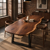 Long freeform wood table top with rippling live edge sides and warm grain in an industrial loft dining room with exposed brick