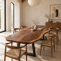 Long freeform wood table top with rippling live edge sides and warm grain in a bright open plan dining room