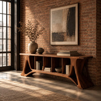 Long console table with flared sculpted legs and a row of narrow open cubbies in an industrial loft entryway with exposed brick