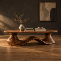 Long oval coffee table on a flowing wave shaped wooden pedestal base in a dark studio against a charcoal plaster wall
