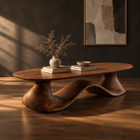 Long oval coffee table on a flowing wave shaped wooden pedestal base, three-quarter view showing the grain